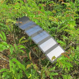 Foldable solar panel attached to a tree branch with green foliage in the background