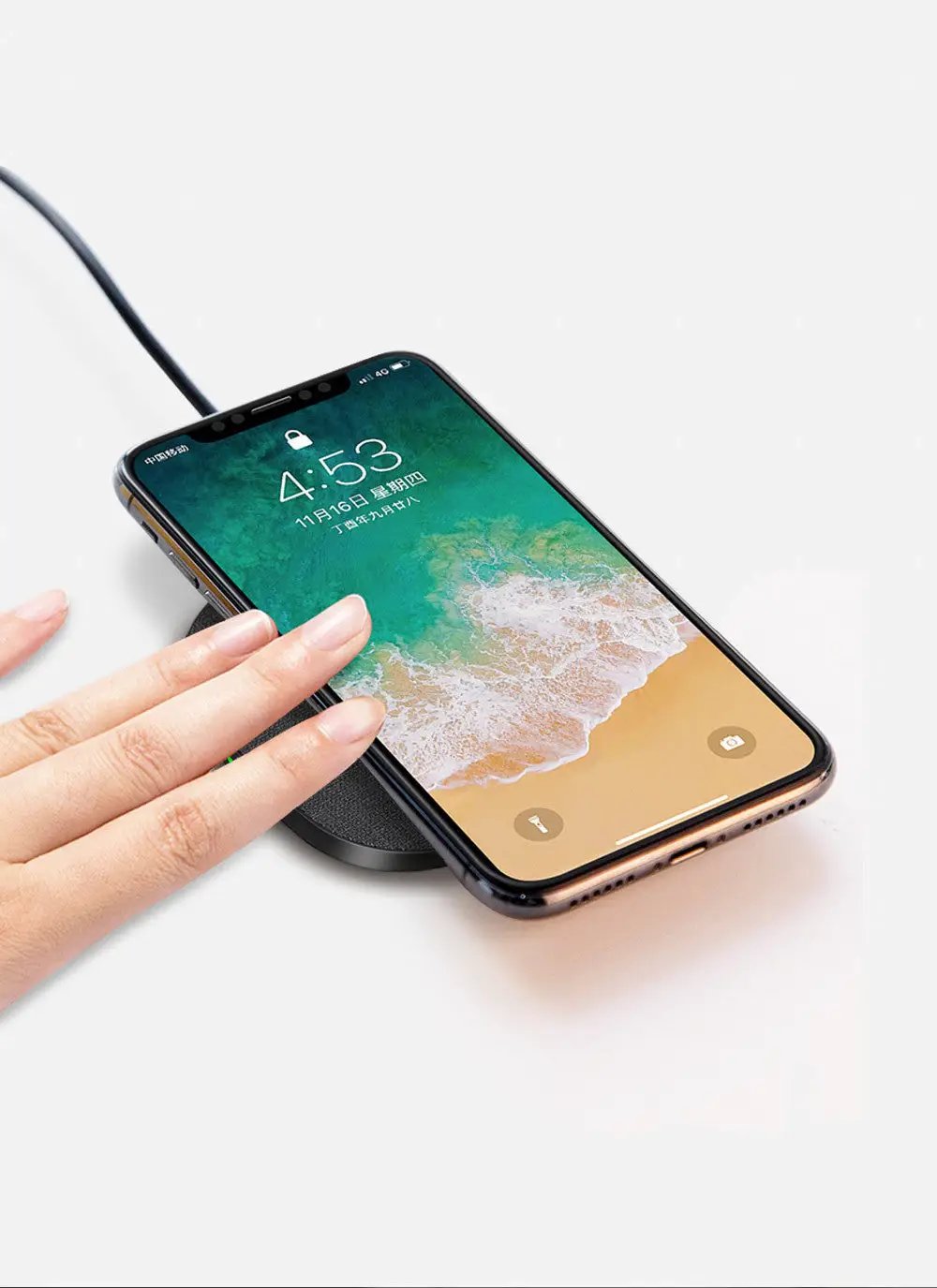 Smartphone being charged on a wireless charging pad with a hand holding it.
